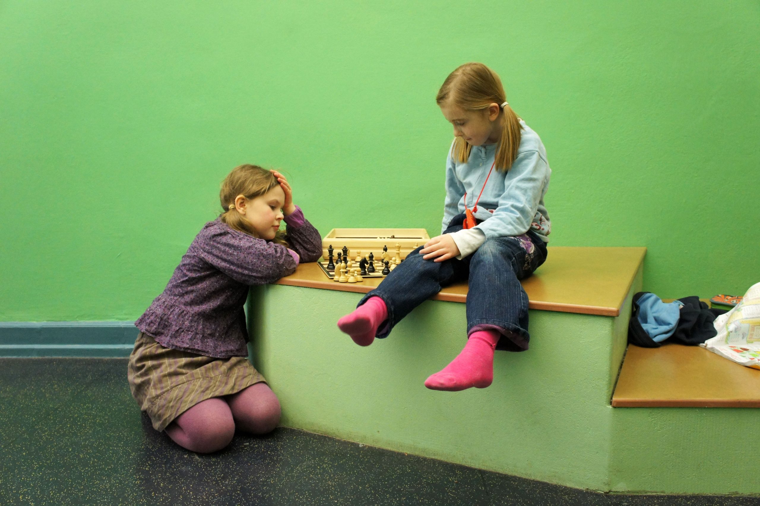 Zwei Kinder lernen spielerisch auf einem festen Sitzelelement im Flur.