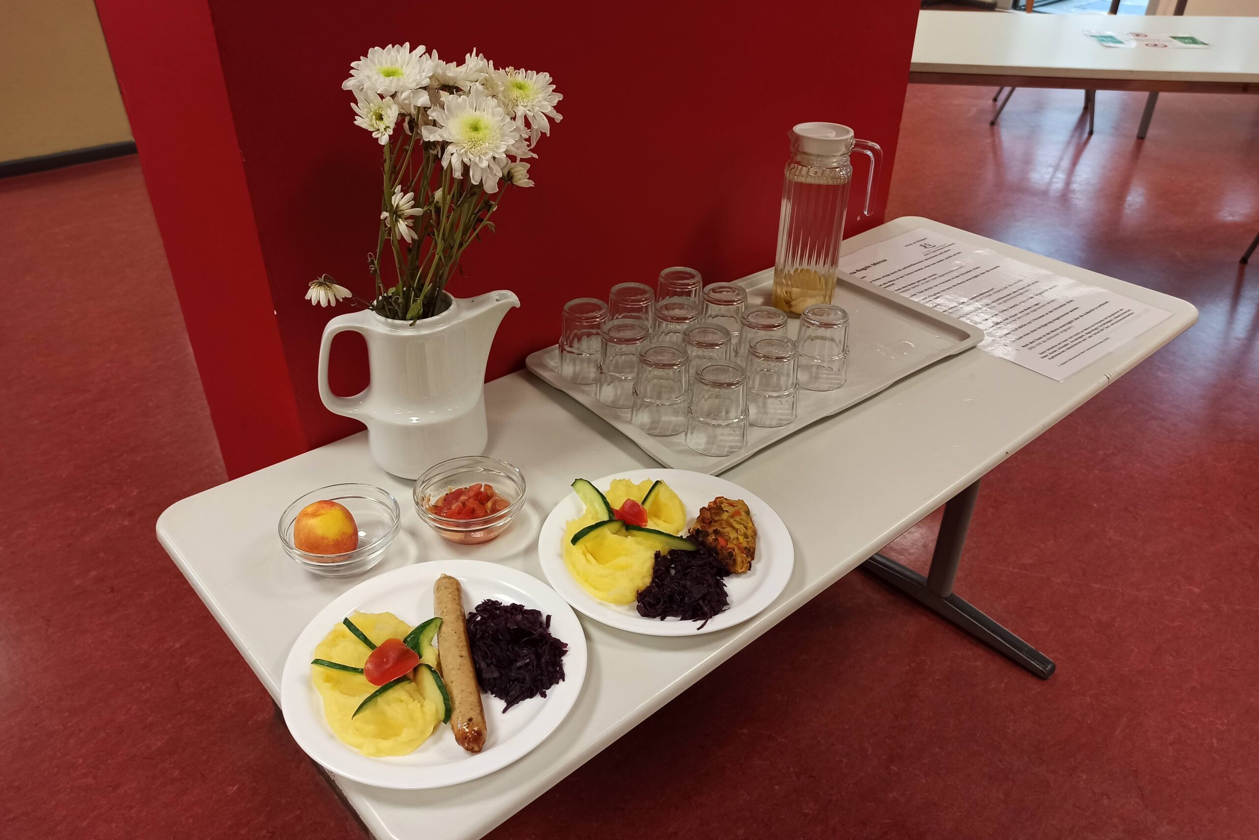 Musteressen mit Getränketablett und Blumenstrauß in einer Schulmensa